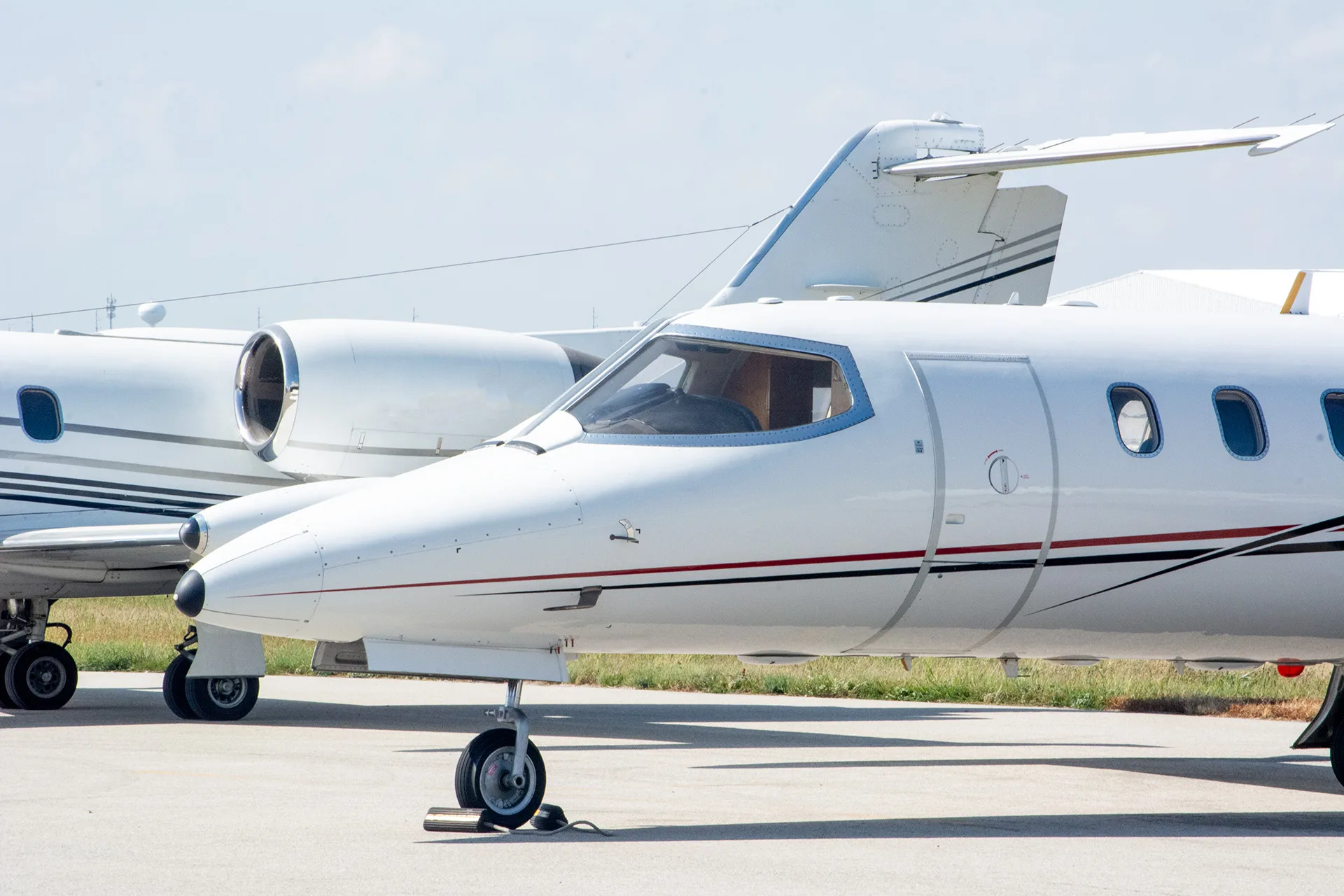 Side view of a Learjet parked on the tarmac, with another Learjet visible in the background.